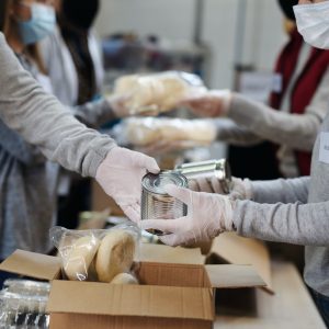 Group of volunteers in community donation center, food bank and coronavirus concept.